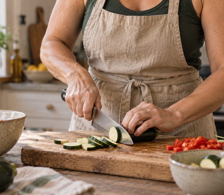 Manos de una mujer cortando verdura en su cocina